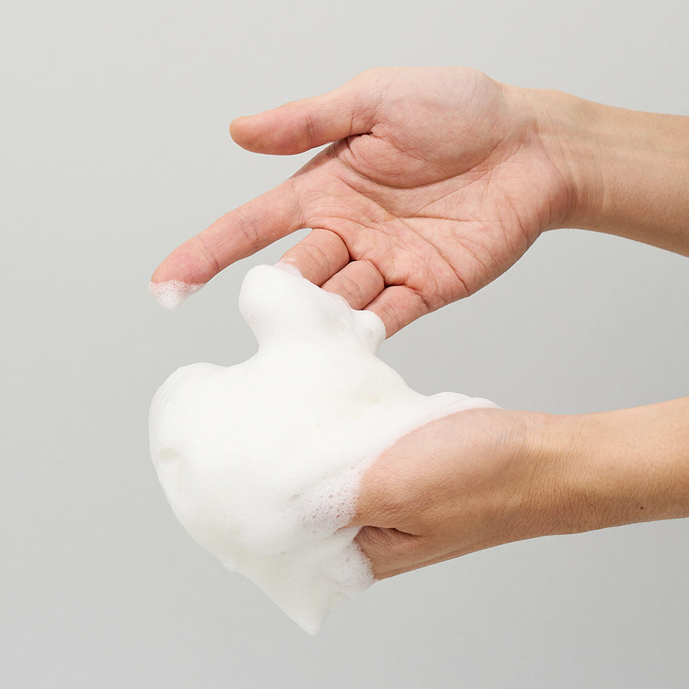 Hand holding a ball of white foam against a gray background