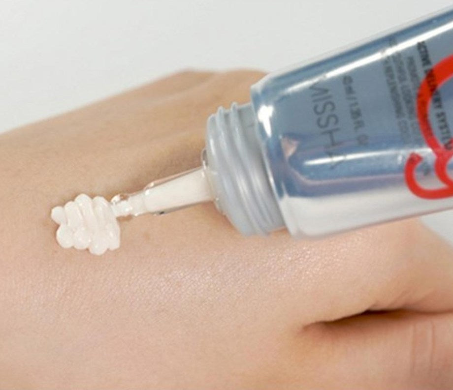 Close-up of a hand applying a cosmetic product from a tube labeled 'MISSHA'.