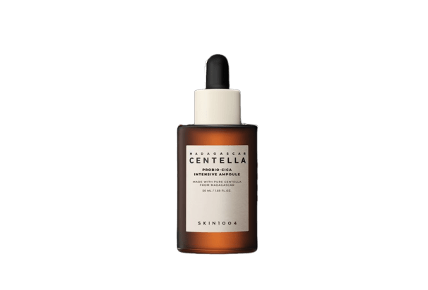 A bottle of SKIN1004 PROBIO-CICA INTENSIVE AMPOULE, which is a skin care product, with a dropper and a label that includes the product name and the word 'Centella'. The background is green and smooth.