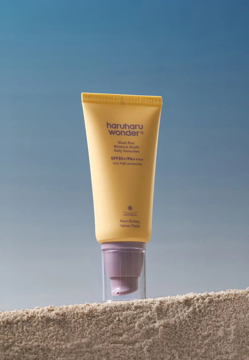 Haruhu Wonder sunscreen tube on a textured surface with a blue gradient background