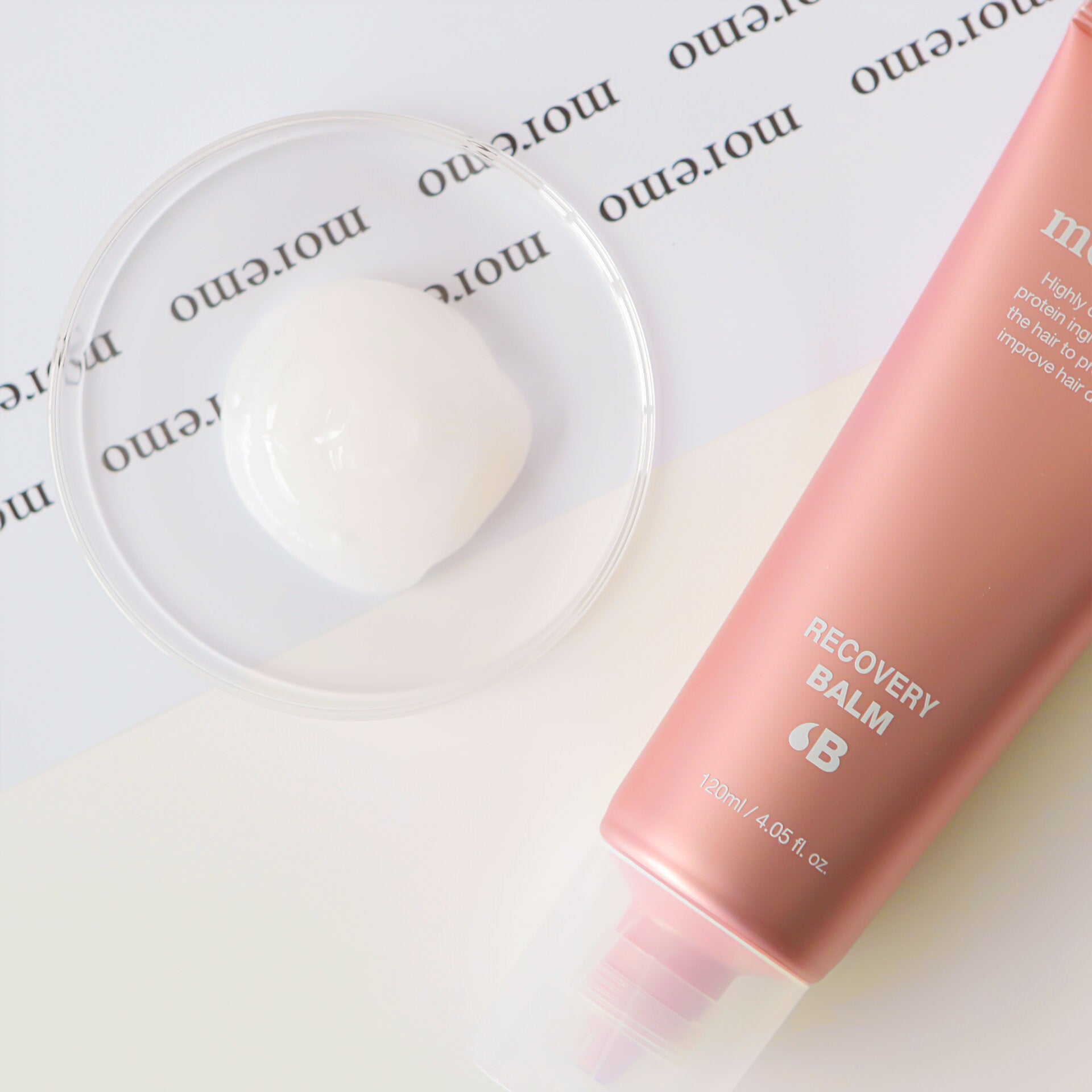 Pink 'Recovery Balm' bottle with cap on a white surface with 'moremo' branding.