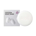 A packaged Cocoon Soap Mask by SKIN1004, which is a bar of soap next to its white and green packaging box displaying the product name and an image of silkworms.